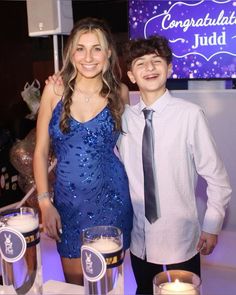 two people standing next to each other in front of a table with drinks and candles