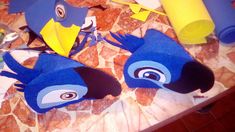 two blue birds made out of toilet paper on top of a table next to rolled up papers