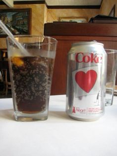 a can of coke next to a glass filled with soda