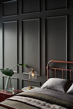 a bedroom with black walls and a metal bed frame, along with a green plant in a glass vase