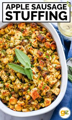 an apple sausage stuffing in a white casserole dish with sage leaves on top