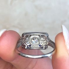 a person holding a ring in their hand, with the diamond on it's side