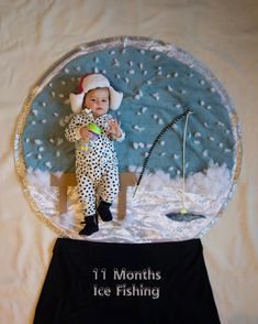 a baby in a snow globe with fishing gear on it's feet and the words 11 months ice fishing