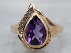 "Here we've taken a vintage gold and champagne diamond mounting and set it with our own stone! This is a wonderful gem, an amethyst with precise faceting and with rich, deep color. The teardrop, pear-shaped cut reflects a great deal of light from within the stone! This luxurious piece will transition well from office to evening! Metal: 14K Yellow Gold Gem: Amethyst 1.70 Carats Gem Measurements: 9.4 x 6.7 mm, Pear Accents: 5 Diamonds totaling .08 Carats, SI in Clarity, Champagne in Color  Ring Si Formal Teardrop Amethyst Ring In Fine Jewelry Style, Elegant Teardrop Amethyst Gemstone Ring, Elegant Pear-shaped Amethyst Ring For Formal Occasions, Formal Pear-shaped Amethyst Ring With Prong Setting, Elegant Formal Pear-shaped Amethyst Ring, Elegant Teardrop Amethyst Ring For Formal Occasions, Teardrop Amethyst Ring For Anniversary, Teardrop Amethyst Ring For Formal Occasions, Formal Teardrop Amethyst Ring