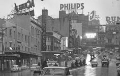 an old black and white photo of cars driving down the street