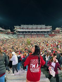 a woman in a red shirt stands at the end of a stadium