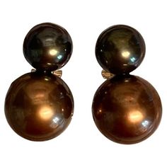 Black and bronze colored Tahitian pearls are featured in these Due Perla (two pearl) drop earrings. The black pearl measures 9mm. It is very dark with the slightest undertone of pistachio. The larger pearl measures 12.5mm. It is a rich bronze color. Both pearls are gem quality with excellent finish and luster. The pearl mountings are 18k yellow gold with posts and omega clip backs for added security. These tailored and business-like earrings are a one-of-a-kind creation by master goldsmith Micha The Black Pearl, E Business, Tahitian Pearls, Pearl Drop Earrings, Black Pearl, Tahiti, Pearl Drop, Bronze Color, Pistachio