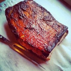 a piece of meat sitting on top of a table next to a knife and fork