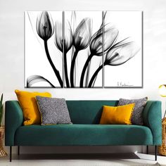 three black and white flowers on a wall above a green couch in a living room