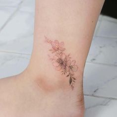 a small tattoo on the ankle of a woman's foot, with pink flowers