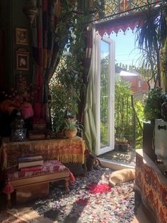 a living room filled with lots of plants next to an open door that leads to a balcony