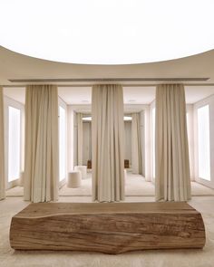 an empty room with white curtains and a large wooden slab