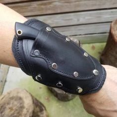 a man wearing a black leather wristband with metal rivets on his arm