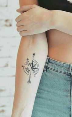 a woman's arm with a tattoo on it that has an arrow and compass