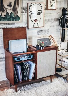 a record player sitting on top of a wooden cabinet next to a wall with pictures