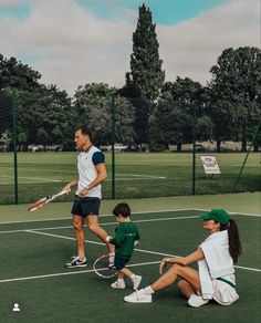 a man and two children are playing tennis on the court