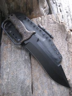 a large knife laying on top of a rock covered in metal rivets and fur