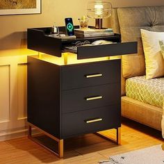 a night stand with two drawers and a phone on it in front of a couch