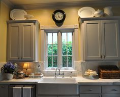 a kitchen with gray cabinets and a clock on the wall