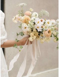 a bridal holding a bouquet of flowers in her hand and wearing a white dress