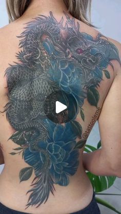 a woman with a dragon tattoo on her back is looking at the camera and has one hand in her pocket