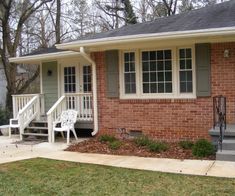 a brick house with steps leading up to the front door and two chairs on the porch