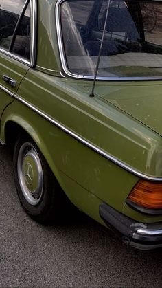 an old green car is parked on the street