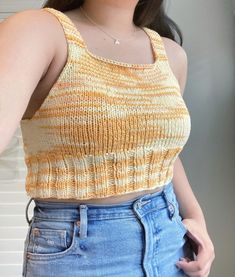 a woman wearing a yellow and white striped tank top with her hands in her pockets