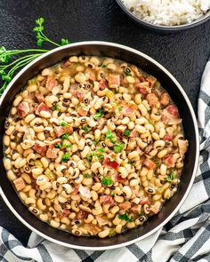 a skillet filled with beans, ham and rice on top of a checkered table cloth