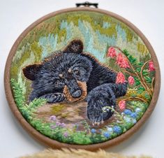 a black bear is laying down on the ground in front of some flowers and plants