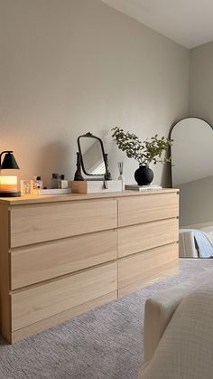 a bedroom with a dresser, mirror and lamp on the side table in front of it