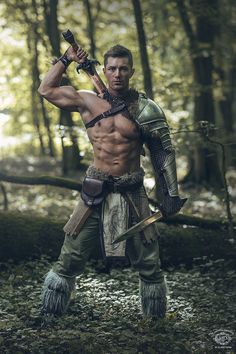 a man dressed as a warrior holding two swords in his hands and posing for the camera