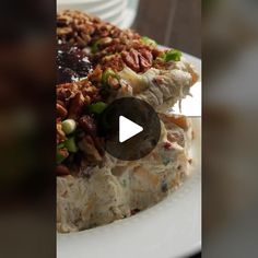 a white plate topped with food covered in nuts and sauce on top of a wooden table