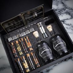 an assortment of liquor bottles in a black box on a marble countertop with instructions