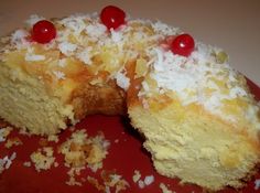 a piece of cake with coconut and cherries on top is cut in half to show the inside