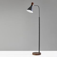 a black floor lamp with a wooden base on a white table in front of a gray wall