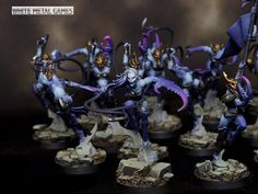 some white metal games figurines with purple and gold paint on them, all holding swords