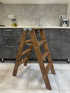 a wooden step stool sitting on top of a kitchen floor