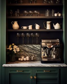 a coffee maker on top of a counter in front of green cupboards and shelves