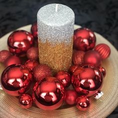 a candle surrounded by red ornaments on a plate