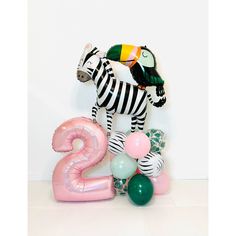 a number two balloon with a zebra and bird on it next to some balloons in the shape of numbers