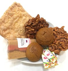 a white plate topped with cookies, nuts and other food items next to each other