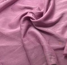 an unmade bed with pink sheets and pillows