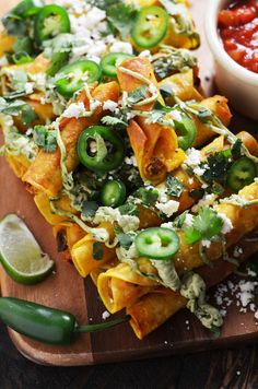 nachos with cheese, jalapenos and salsa on a cutting board