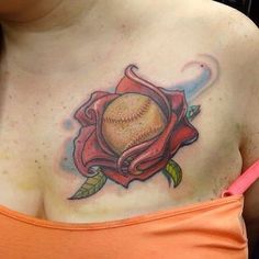 a woman's chest with a baseball and rose tattoo on her left side shoulder