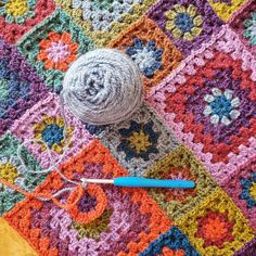 a crocheted blanket with a ball of yarn next to it and a knitting needle