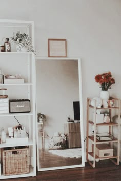 a mirror sitting on top of a wooden floor next to a shelf filled with items