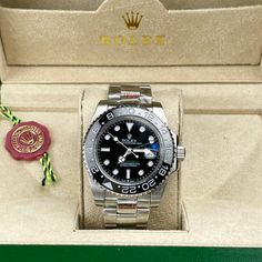 This timepiece is a Rolex GMT-Master II, a renowned model celebrated for its dual time-zone functionality and robust design. Its black dial with luminous markers ensures easy readability, complemented by a black Cerachrom ceramic bezel with a 24-hour scale. The watch features the classic Oyster bracelet in stainless steel, providing durability and comfort. Powered by either the Caliber 3186 or 3285, this watch guarantees exceptional precision and a power reserve of up to 70 hour. Designer Black Diamond Watch With Diamond Hour Markers, Designer Watches With Analog Display And Round Dial, Luxury Black Watch With Analog Display, Designer Analog Watch With Round Dial, Luxury Black Watch Accessories With Analog Display, Luxury Black Analog Watch, Luxury Black Analog Display Watch, Designer Analog Display Watch, Black Chronograph Watch With Diamond Hour Markers