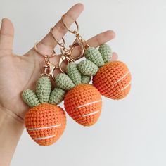 two crocheted fruit key chains are being held by a person's hand