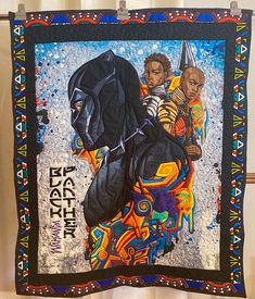 a quilt hanging up on a wall with an image of two black men in the background